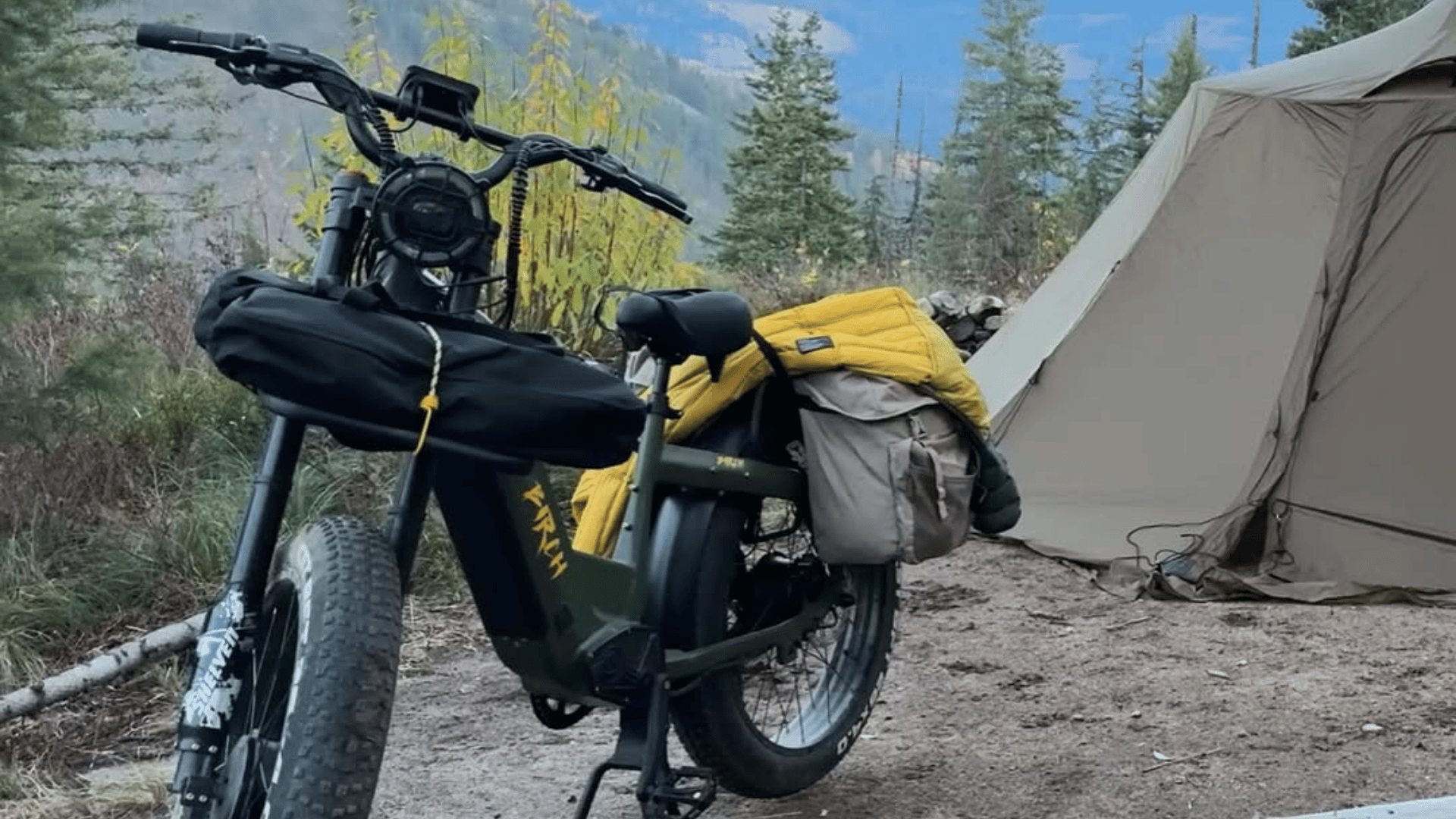 hunting ebike packed with gear in front of the wilderness and a camping tent